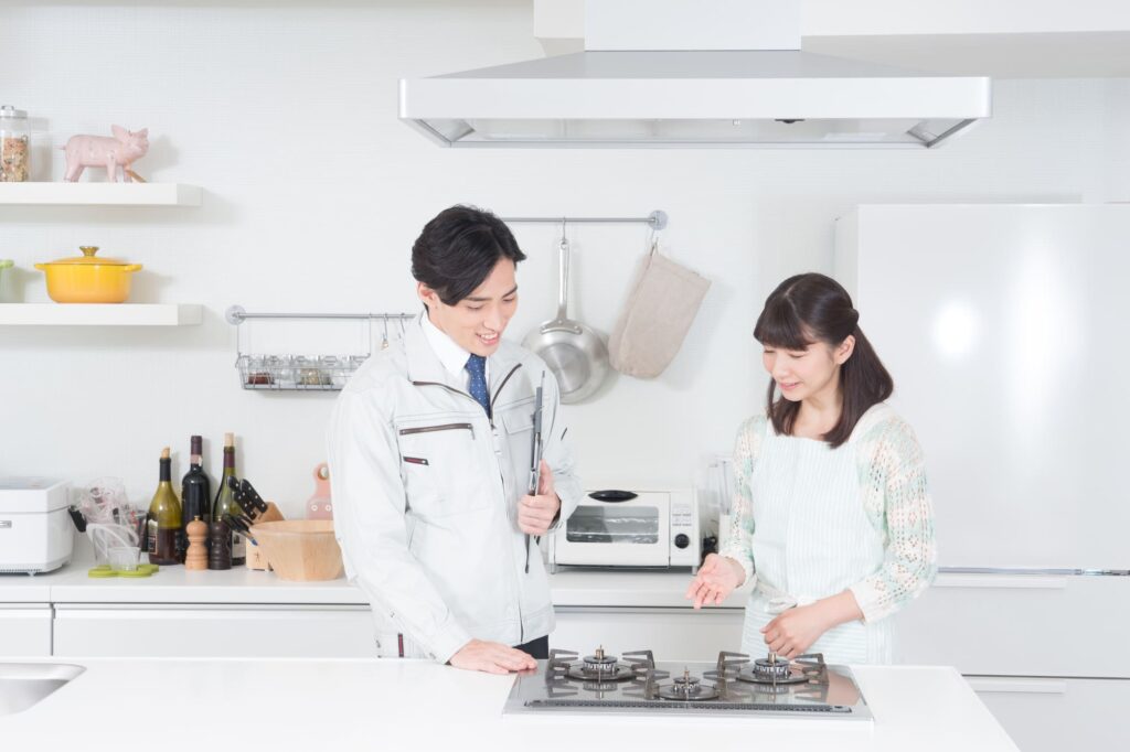 リフォーム業者からガスコンロの説明を受ける主婦