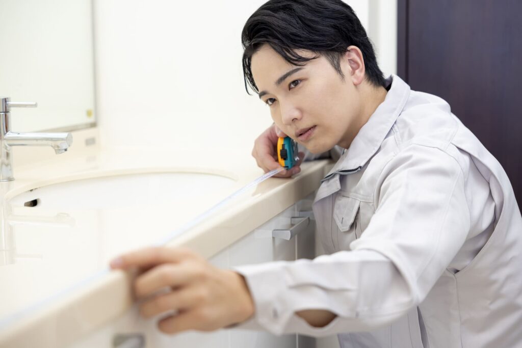 洗面台のサイズを測定している作業員